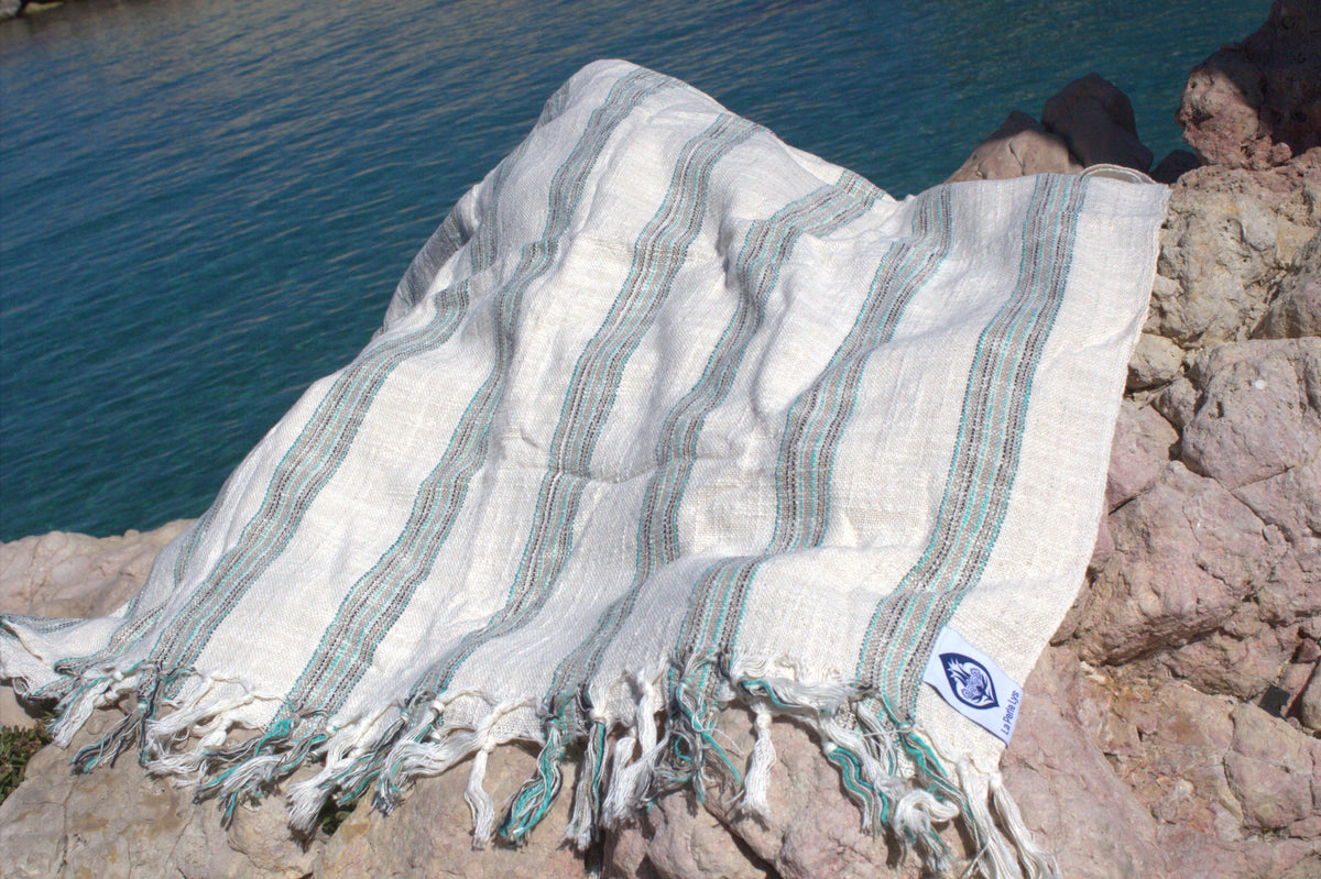 Peshtemal premium en coton turc déplié sur le sable de Méditerranée, La Perle Lys
